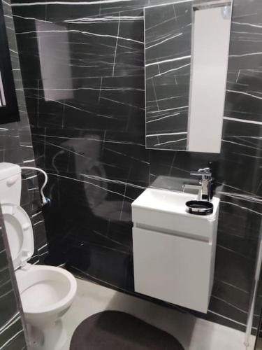a black tiled bathroom with a toilet and a sink at סוויט דרים בגושן in Qiryat Motzkin