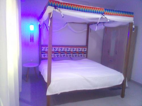 1 dormitorio con cama con dosel y luces moradas en Kokrobitey Apartments-GAL, en Accra