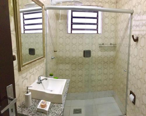 uma casa de banho com um lavatório e uma cabina de duche em vidro. em Nossa Casa Novo Hamburgo em Novo Hamburgo