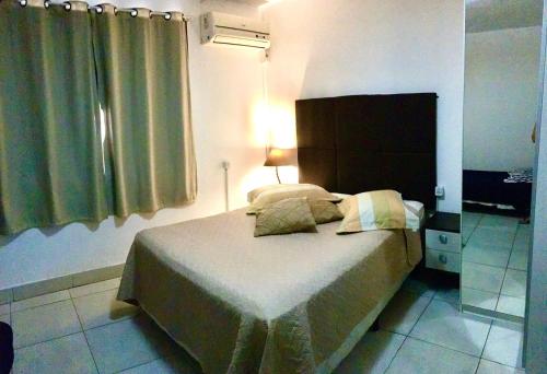 a bedroom with a bed with a headboard and a window at Nossa Casa Novo Hamburgo in Novo Hamburgo