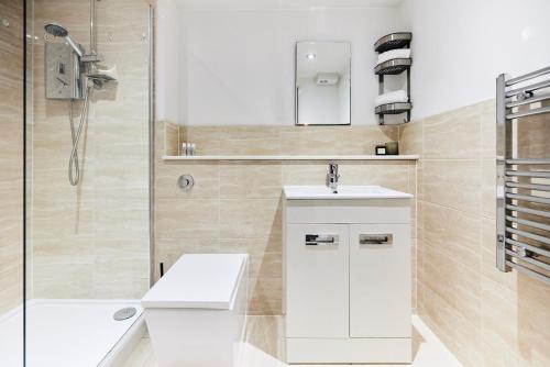 baño blanco con ducha y lavamanos en The Waltham Forest Escape - Adorable 2BDR Flat en Londres