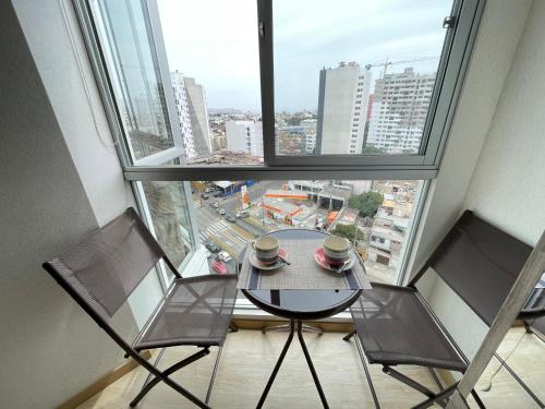 una mesa y dos sillas frente a una ventana en Habitación privada con hermosa vista de Barranco, en Lima