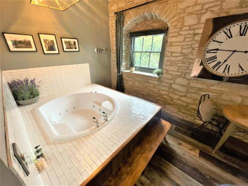 a large bath tub in a bathroom with a large clock at Marske Stables, Yorkshire Dales in Marske