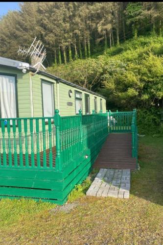 una valla verde frente a una casa en Van number 123 Beautiful Caravan sleeps 4 to 6 en Aberystwyth