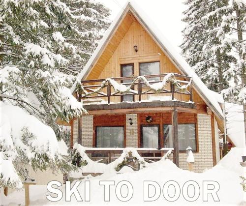 a log cabin in the snow with the words ski to door at Traveland Boutique Resort Poiana Brasov in Poiana Brasov