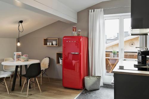 a red refrigerator in a kitchen with a table at Bewegte Berge Apartments in Saalfelden am Steinernen Meer