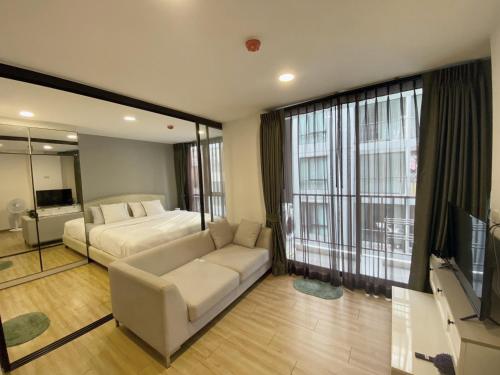 a bedroom with a bed and a couch and a tv at Notthing Hill Charoenkrung93 Condominium in Godown