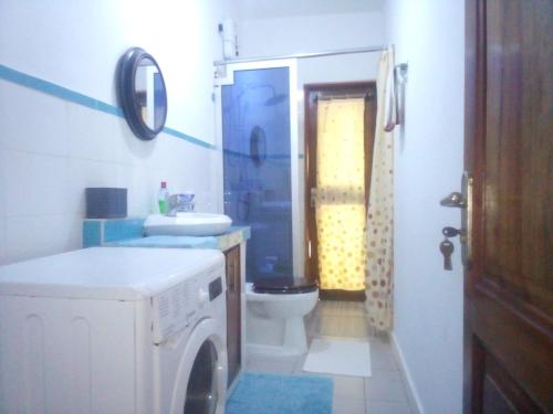a bathroom with a washing machine and a toilet at Kokrobitey Apartments-GAL in Accra