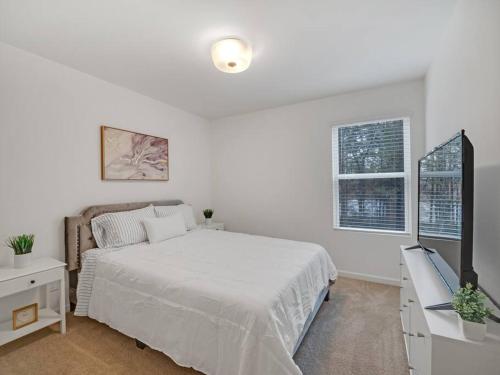 ein weißes Schlafzimmer mit einem Bett und einem Fernseher in der Unterkunft Gorgeous New Townhome/Charlotte! in Charlotte