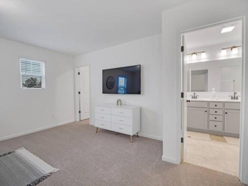 a white bathroom with a sink and a tv at Gorgeous New Townhome/Charlotte! in Charlotte
