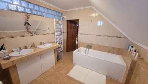 a bathroom with two sinks and a bath tub at Tímea Vendégház Zalaszabar in Zalaszabar