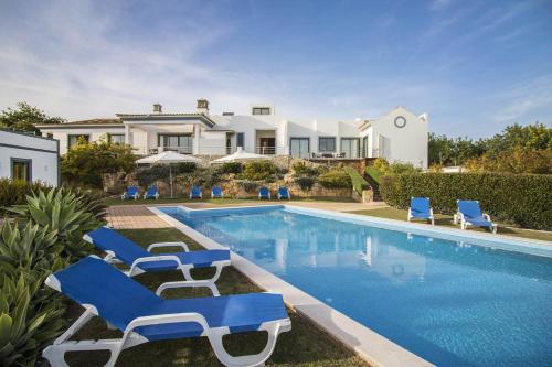 a villa with a swimming pool and blue lounge chairs at Casa Serena in Estói