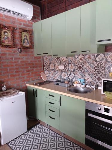 a kitchen with green cabinets and a sink at Njih tri Jelova gora in Užice