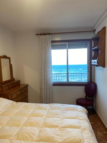 a bedroom with a bed and a window with the ocean at Descans in Cullera