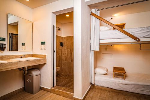 uma casa de banho com um lavatório e um beliche. em Nomads Party Hostel em Cancún