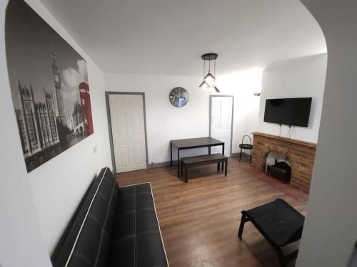 a living room with a black couch and a tv at Kensington Stories - 4 Bed House in Watford