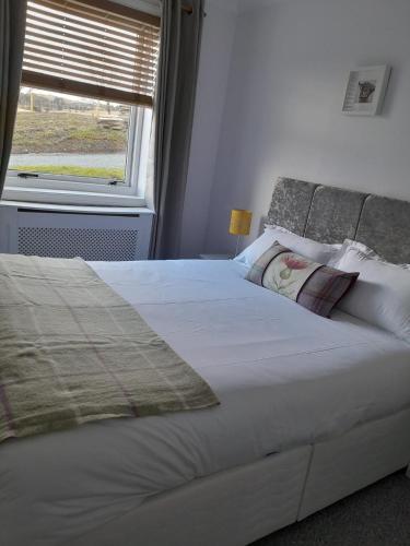 a bedroom with a large white bed with a window at Lealt Falls Apartment in Culnacnoc