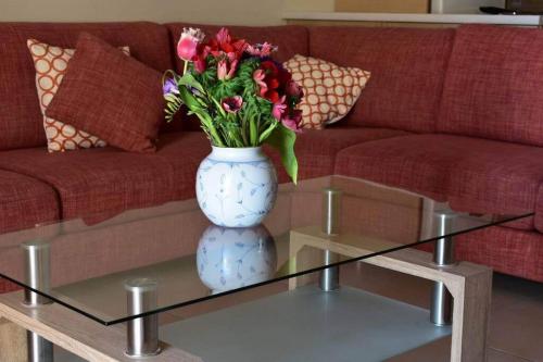 a vase with flowers sitting on a glass table at Stavros Niarhos apartment in Athens