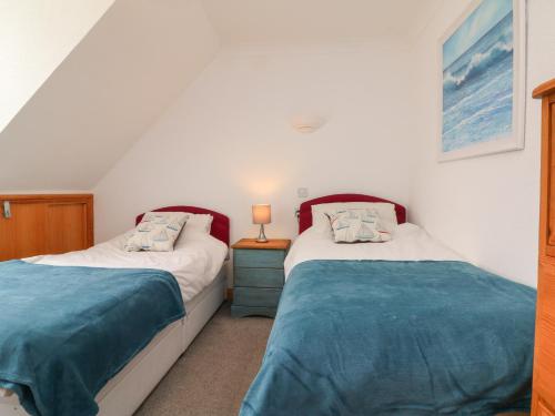 a bedroom with two beds and a table with a lamp at 5 Seymour Villas in Woolacombe