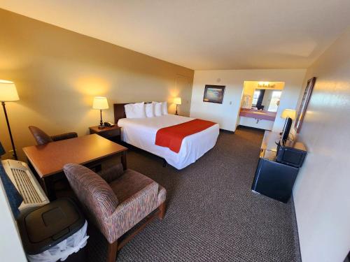 um quarto de hotel com uma cama, uma secretária e uma cadeira em Budget Motel em Burley
