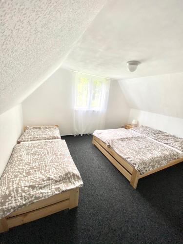 two beds in a room with white walls at Chaloupka Všemily in Jetřichovice