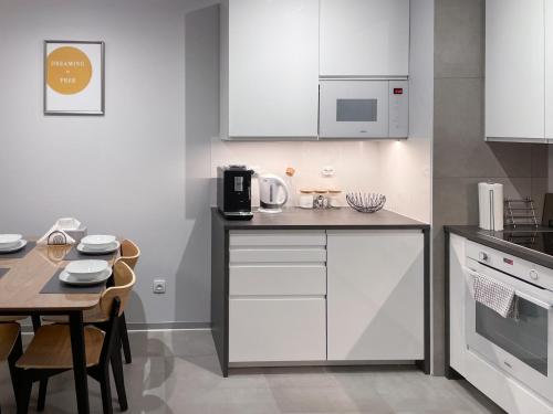 a kitchen with white cabinets and a table with a microwave at Apartament Cudovny in Kudowa-Zdrój