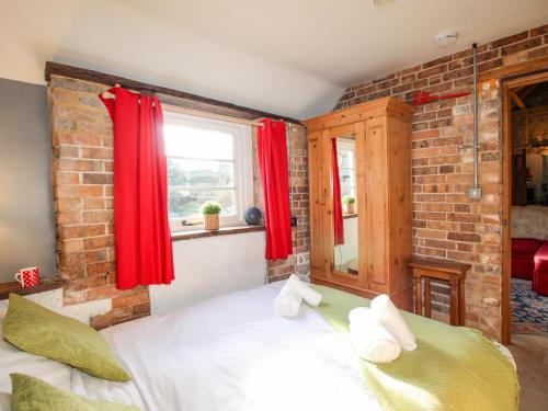 a bedroom with a bed with red curtains and a brick wall at Carnotze in Dorchester