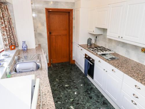 a kitchen with white cabinets and a sink and a stove at Pringles Orchard in Gildingwells