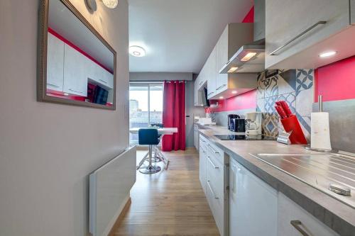 cocina con armarios blancos y paredes rojas en Studio Grammont 4 en Tours