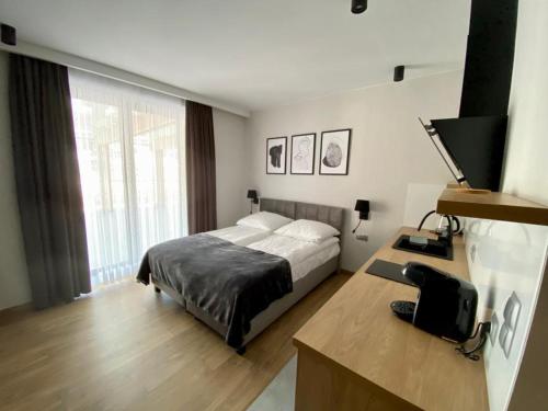 um quarto com uma cama e uma secretária com uma televisão em Apartamenty WIERCHY em Klikuszowa