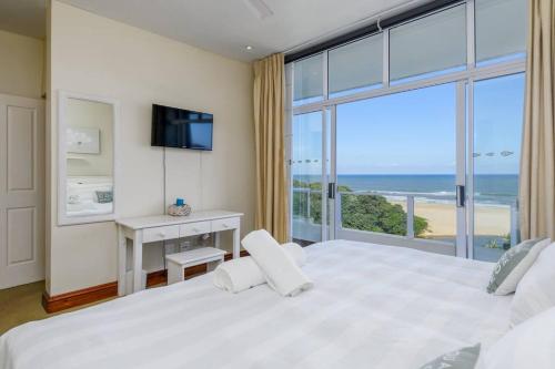 a bedroom with a large white bed with a view of the ocean at 402@ColonialSands in Margate