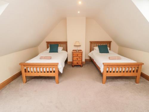 een slaapkamer op zolder met 2 bedden en een nachtkastje bij High Hemmel House in Embleton