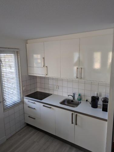 a kitchen with white cabinets and a sink at Amelander Kaap 1 in Hollum