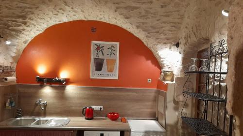 cocina con fregadero y pared de color naranja en Le jardin, en Saint-Martin-dʼArdèche