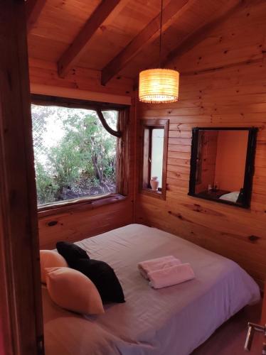 ein Schlafzimmer mit einem Bett in einem Blockhaus in der Unterkunft Cabaña en Bosque Nativo in San Carlos de Bariloche