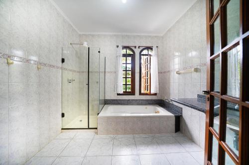 a white bathroom with a tub and a shower at Hotel Pousada Casa Grande in Joanópolis
