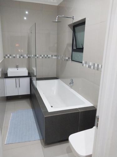 bagno con ampia vasca e lavandino di LND GUEST HOUSE a Bloubergstrand