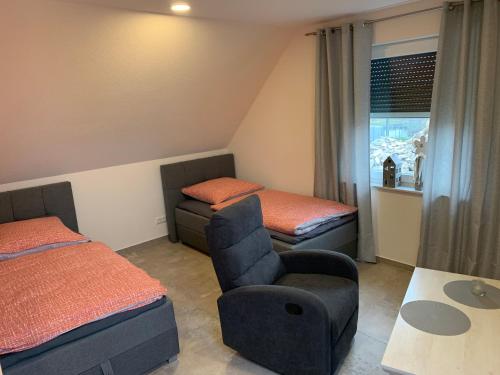 a bedroom with two beds and a chair and a table at Haus Benz für 8 Personen - 4 Zimmer m. Dusche Vollausstattung 1km v. Wittenberge Baustelle A14 Parkplätze Grill Gemeinschaftsküche in Eickerhöfe