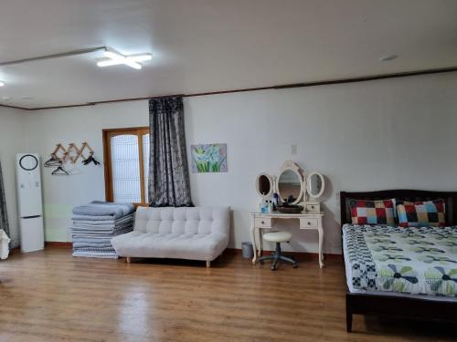 ein Wohnzimmer mit einem Bett und einem weißen Sofa in der Unterkunft Haeansung Pension in Seogwipo