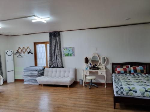 a living room with a bed and a white couch at Haeansung Pension in Seogwipo