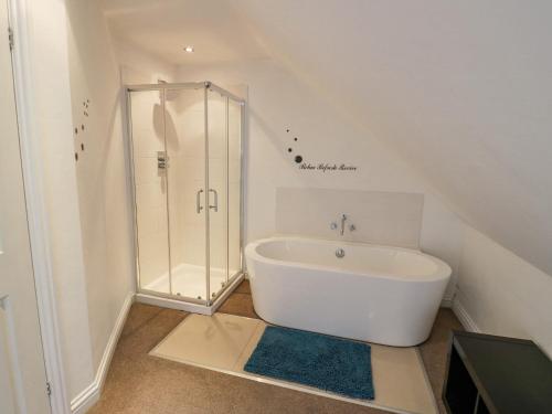 La salle de bains est pourvue d'une douche et d'une baignoire blanche. dans l'établissement Shatterford Lakes, à Bewdley