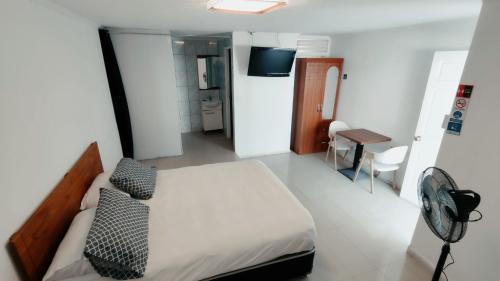 a bedroom with a bed and a desk with a fan at Hotel Flamingo Express in Iquique