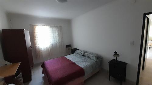 Habitación pequeña con cama y ventana en Alojamiento Los Robles en Olavarría