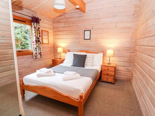 a bedroom with a bed in a wooden cabin at Snowy Owl Lodge in Rhayader