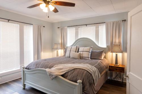 um quarto com uma cama, uma ventoinha de tecto e janelas em Midtown Cottage em Tyler