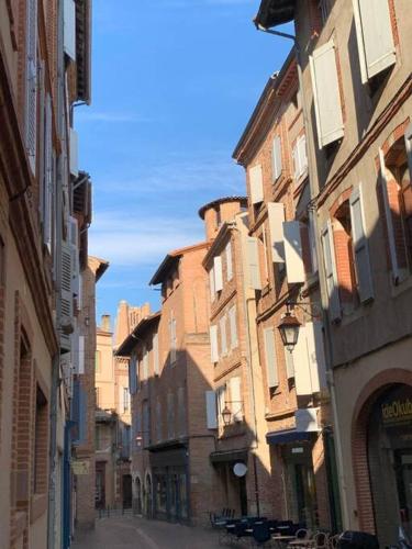 une rue urbaine avec de grands bâtiments dans une ville dans l'établissement Charmant Studio Hyper Centre Proche Cathédrale, à Albi