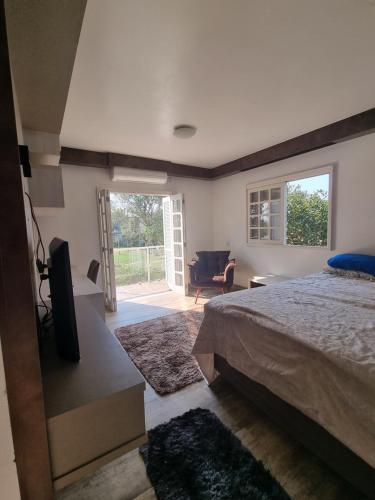 um quarto com uma cama e uma porta de vidro deslizante em Sítio com piscina Hidromassagem com acesso ao Rio Mampituba em Passo de Torres