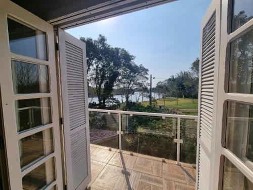 a door to a balcony with a view of a field at Sítio com piscina Hidromassagem com acesso ao Rio Mampituba in Passo de Torres