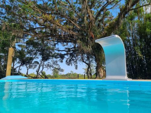 an infinity pool with a tree in the background at Sítio com piscina Hidromassagem com acesso ao Rio Mampituba in Passo de Torres