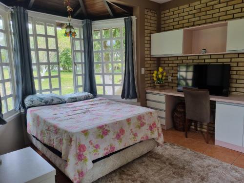 a bedroom with a bed and a desk and a tv at Sítio com piscina Hidromassagem com acesso ao Rio Mampituba in Passo de Torres